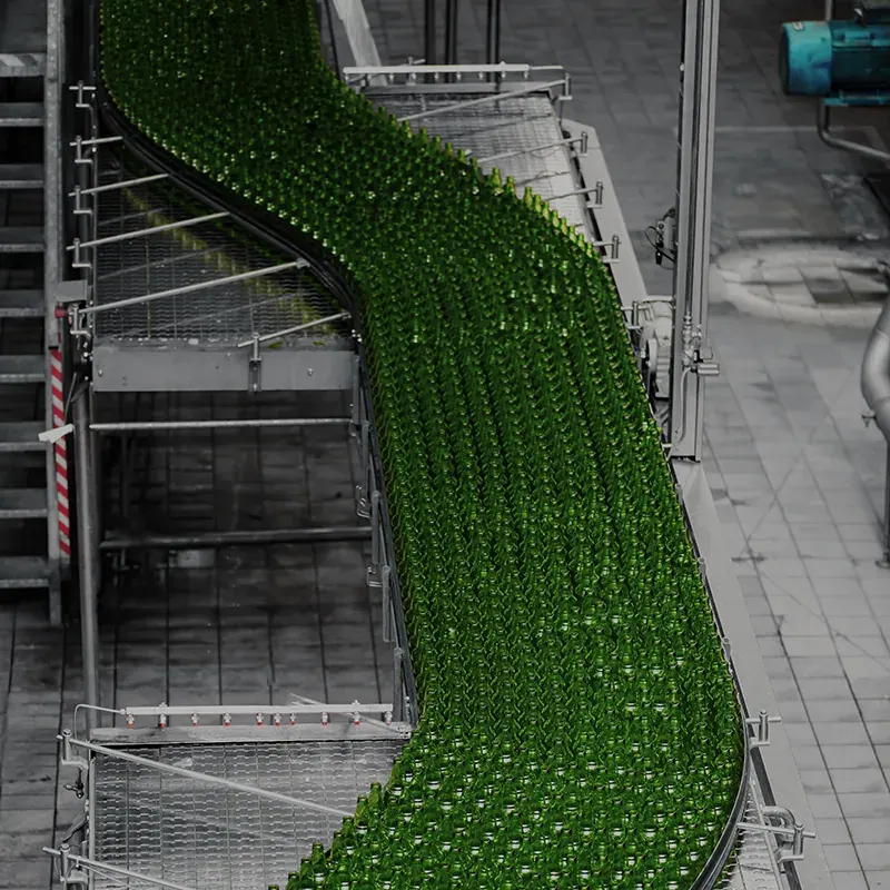 Groene flessen op een transportband in een vullijn