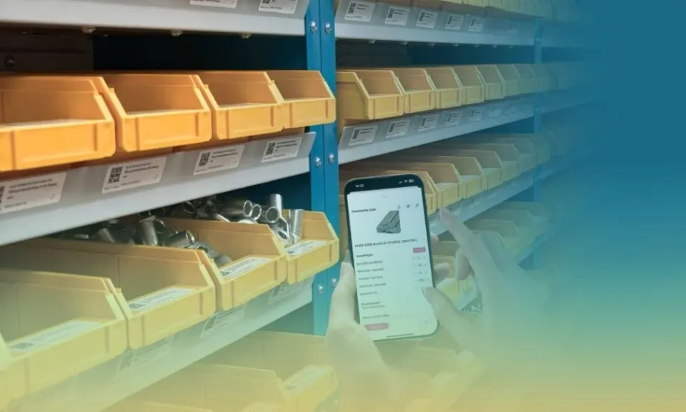 Warehouse racking with labelled bins and an engineer using the app on his phone