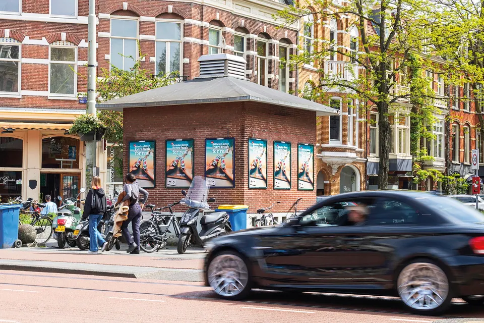 A0 advertising frames on a city building, with traffic passing in front