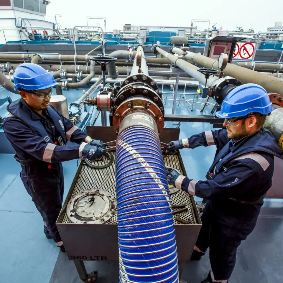 Two CIMS crew members connecting a hose on the deck of a tanker